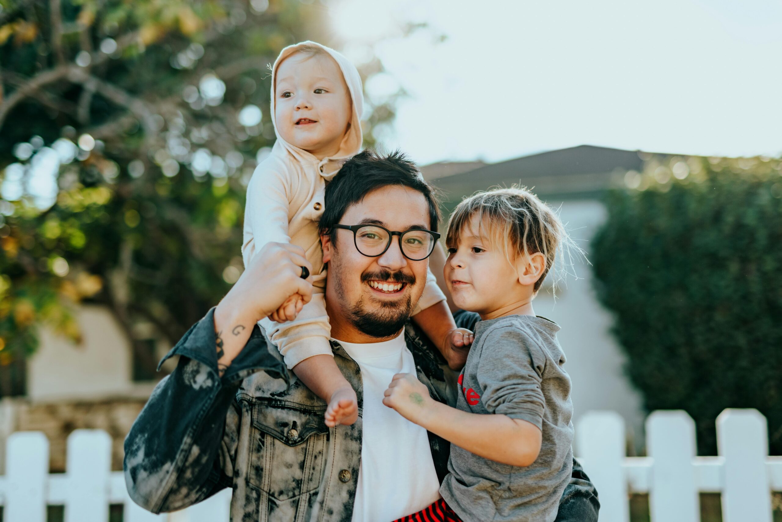 Two kids riding on their father's shoulders.